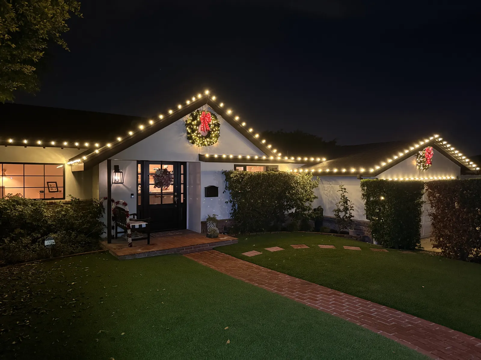 Single-story home in Burbank with warm white roofline lights and lit wreaths on the front gables