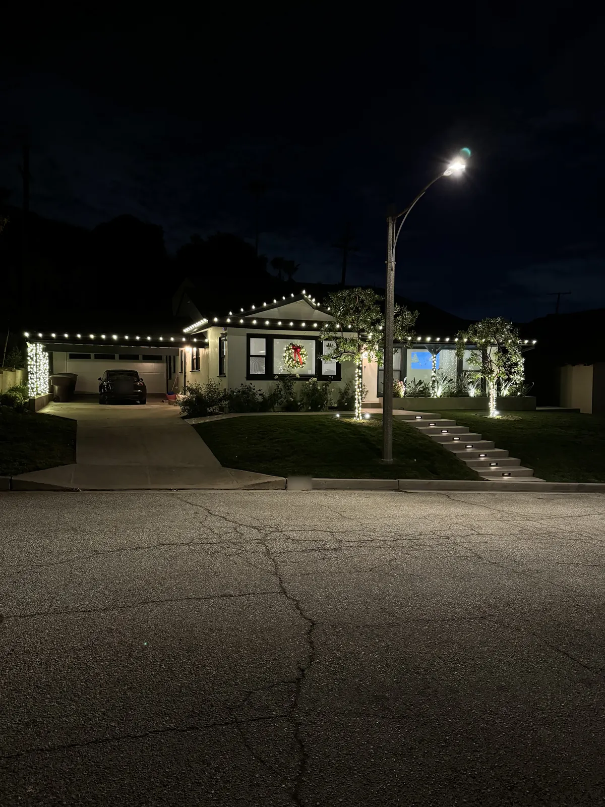 Single-story home in Glendale with warm white roofline lights and light-wrapped trees, seen from the street