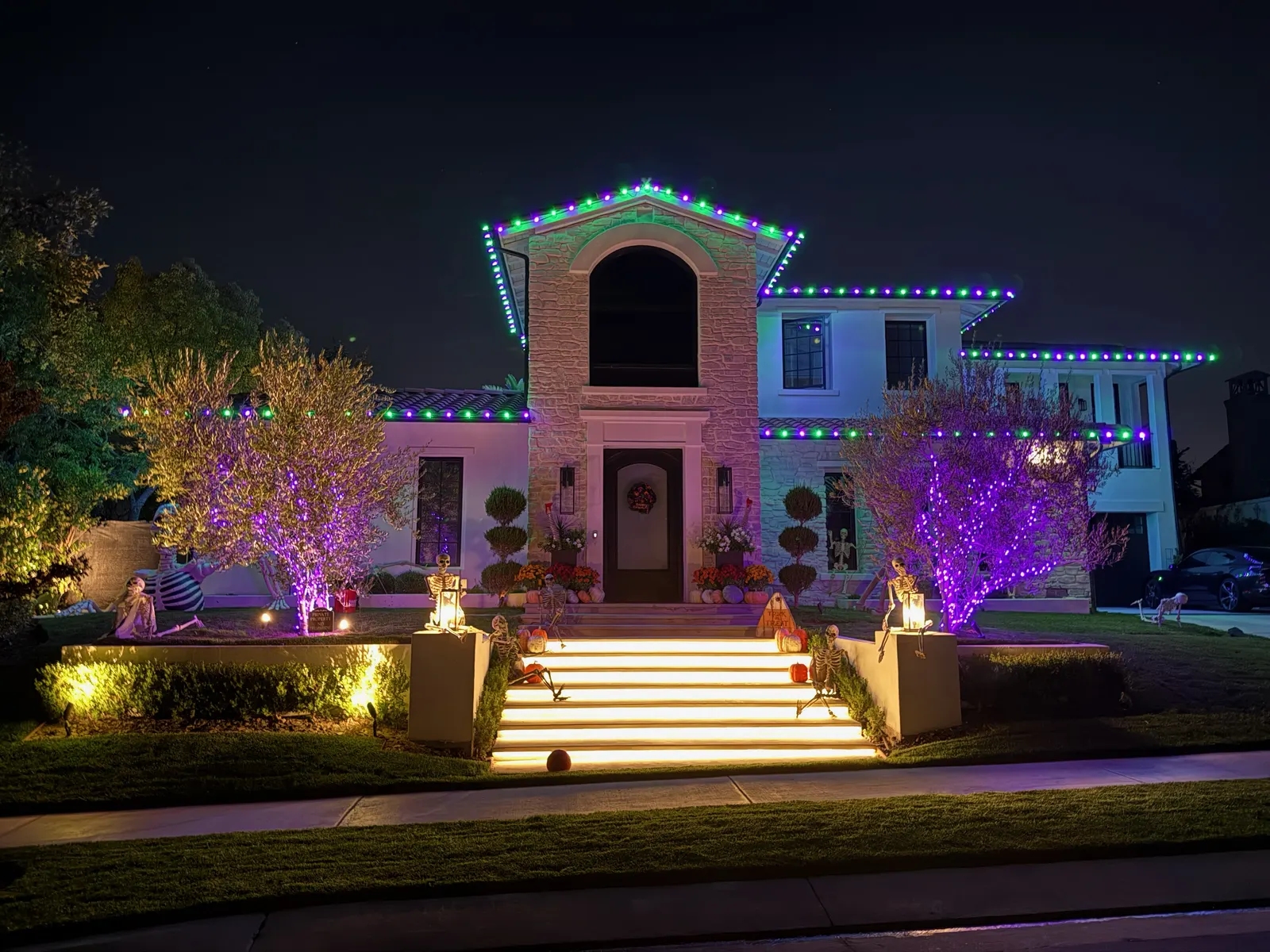 Home with Halloween roofline lights, purple tree lights, and skeleton decorations
