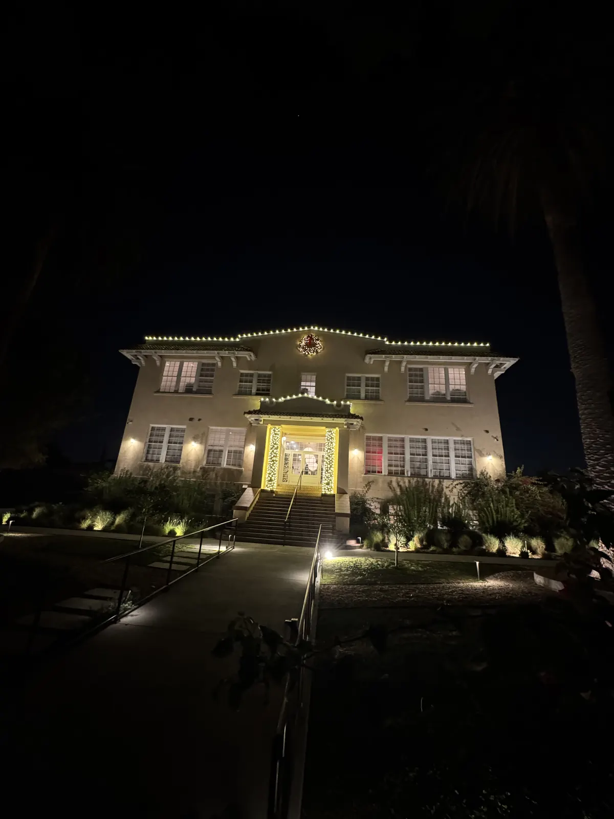 Home at night with warm white roofline lights and lit landscaping along the front walk