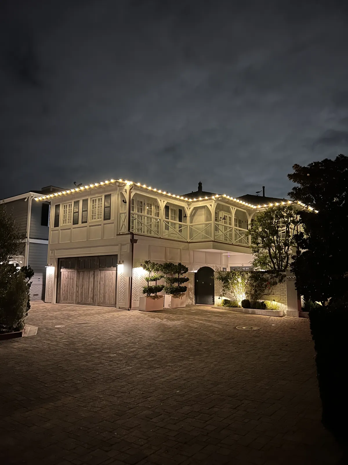 Two-story home in Newport Beach with warm white lights along the roofline and balcony