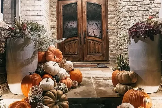 Orange, white, and heirloom pumpkins stacked at a rustic stone doorway