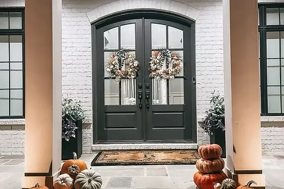 Stacked pumpkin towers and autumn wreaths at an elegant dark front door
