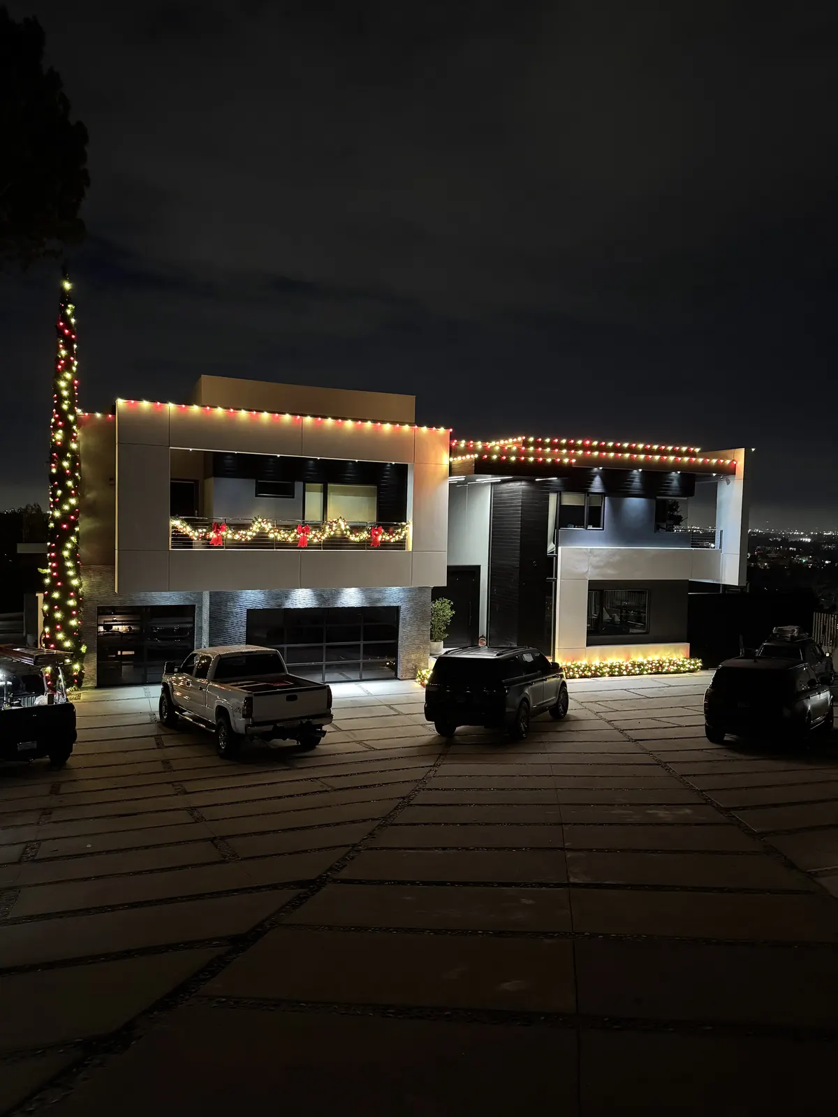 Modern home in Studio City with warm white roofline lights, a light-wrapped tree, and garland on the balcony